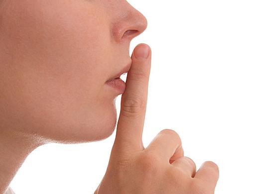 Dieses Foto zeigt einen Mund vor auf den ein Finger, als Zeichen der stille gehalten wird.